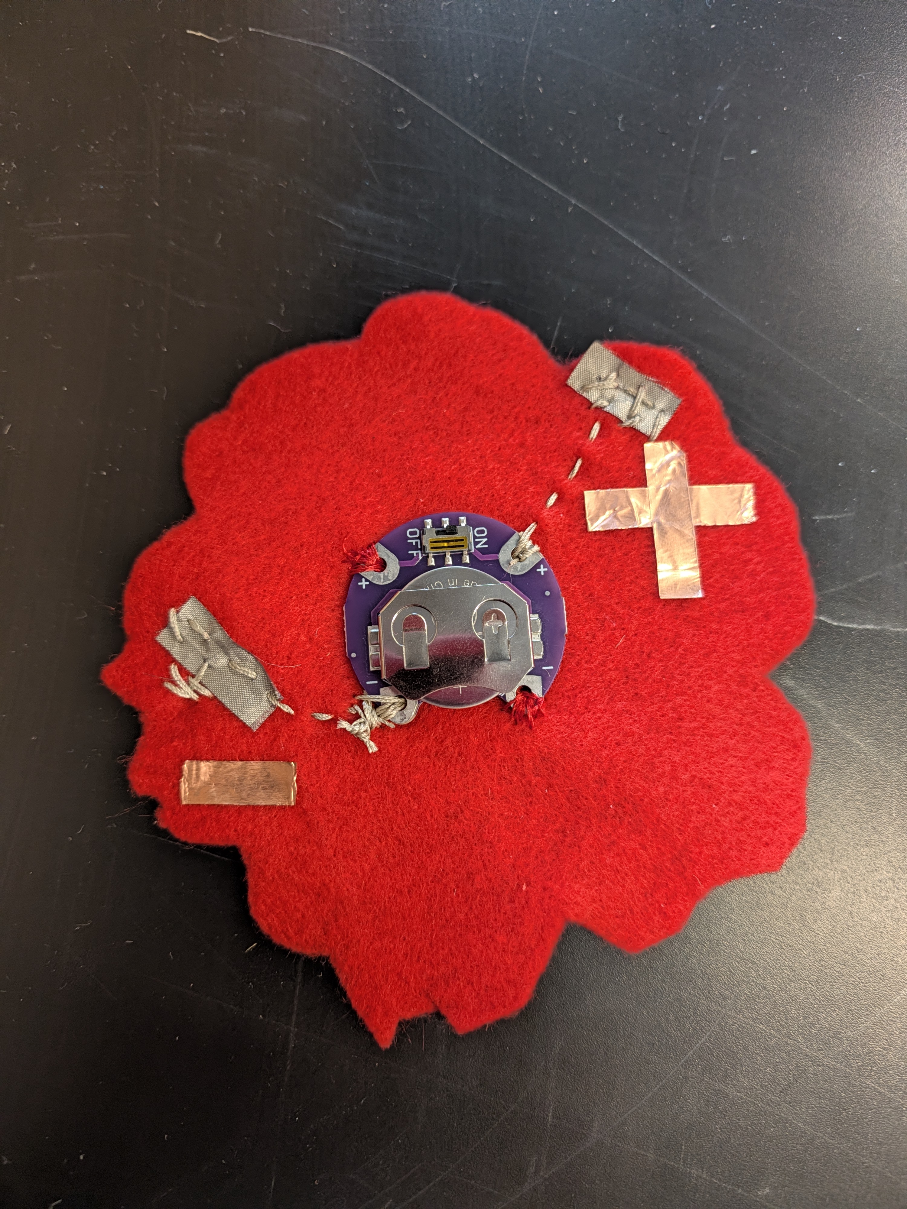 Textile power breakout module with sewable coin-cell holder, conductive fabric pads, and copper tape polarity markers