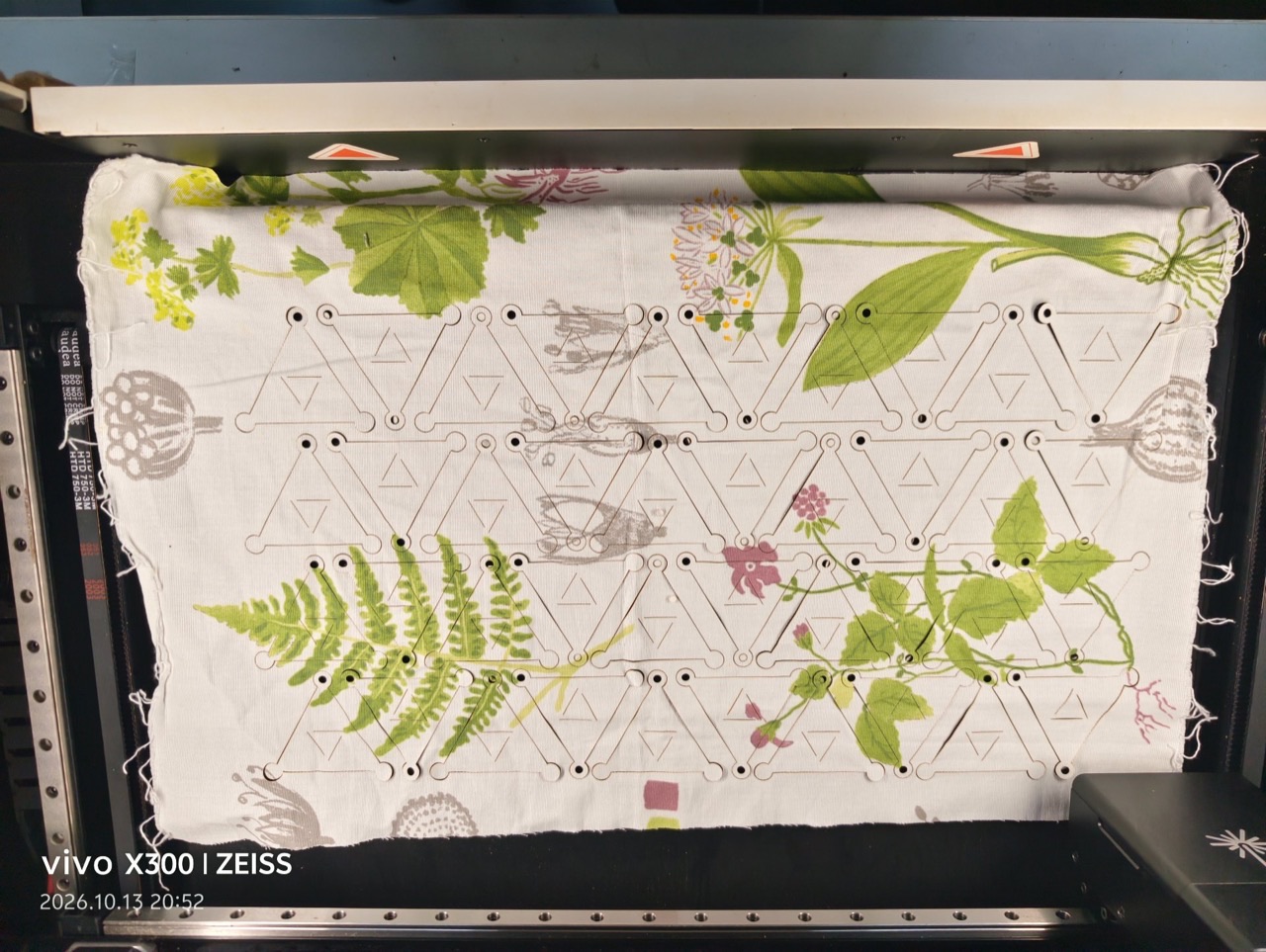 The full tessellated sheet in the Laserbox bed after cutting — triangular modules with vertex holes in printed cotton