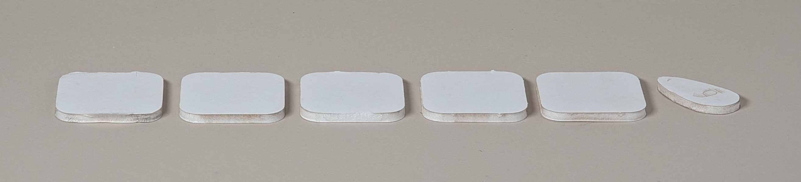 5 rounded corner squares and 1 organic shaped foamcore pieces aligned in a row with torn and melted edges
